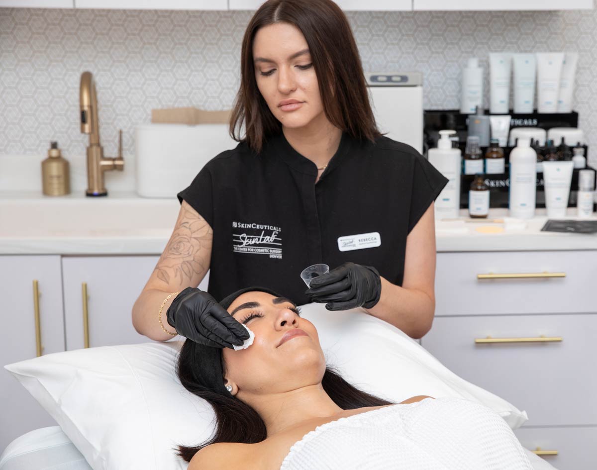 Aesthetic provider applying a professional facial peel treatment to a patient.