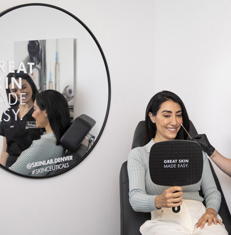 Patient holding a mirror during an injectable treatment consultation.